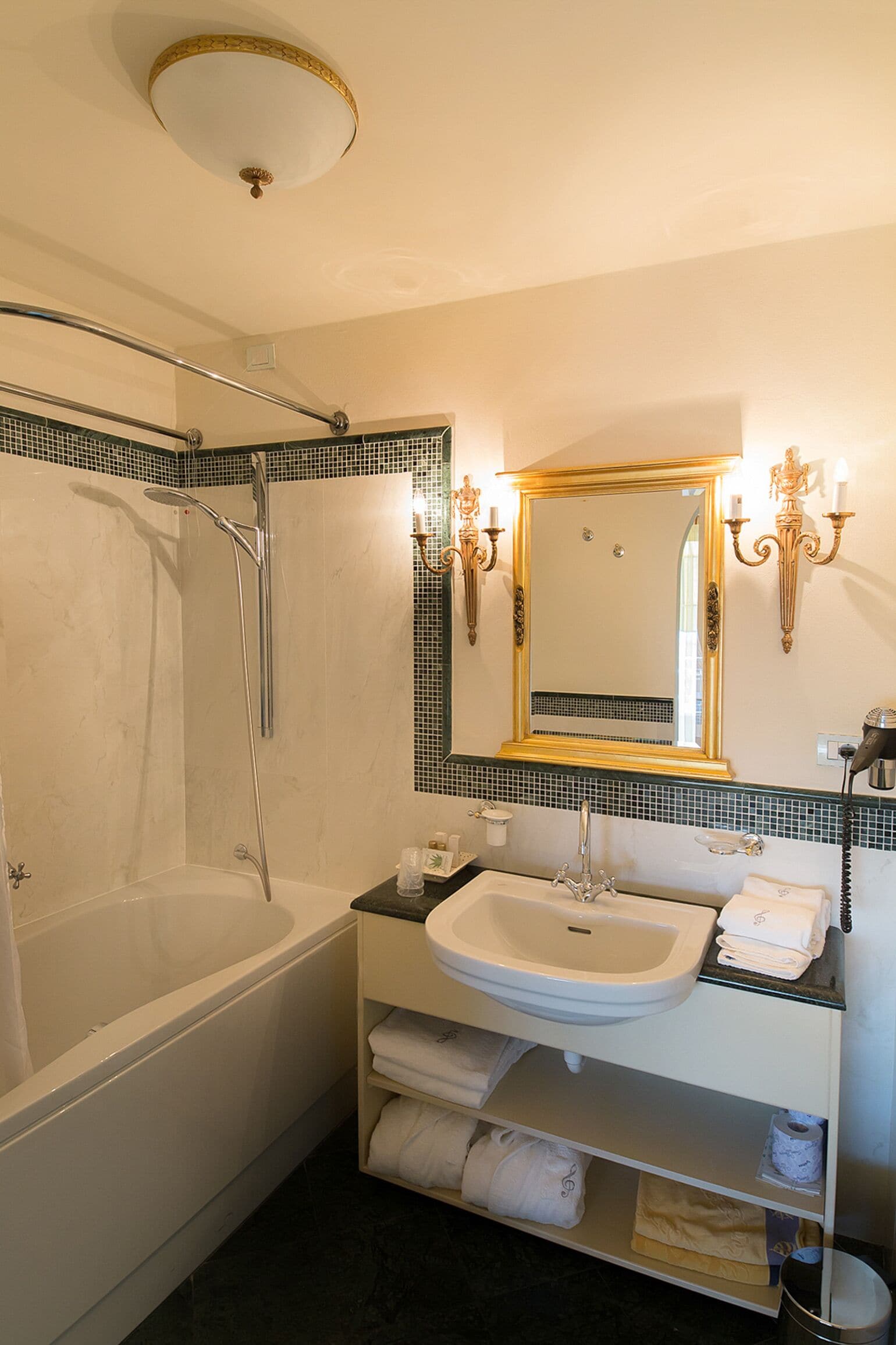 Un baño con bañera, lavamanos, espejo y estante con toallas.