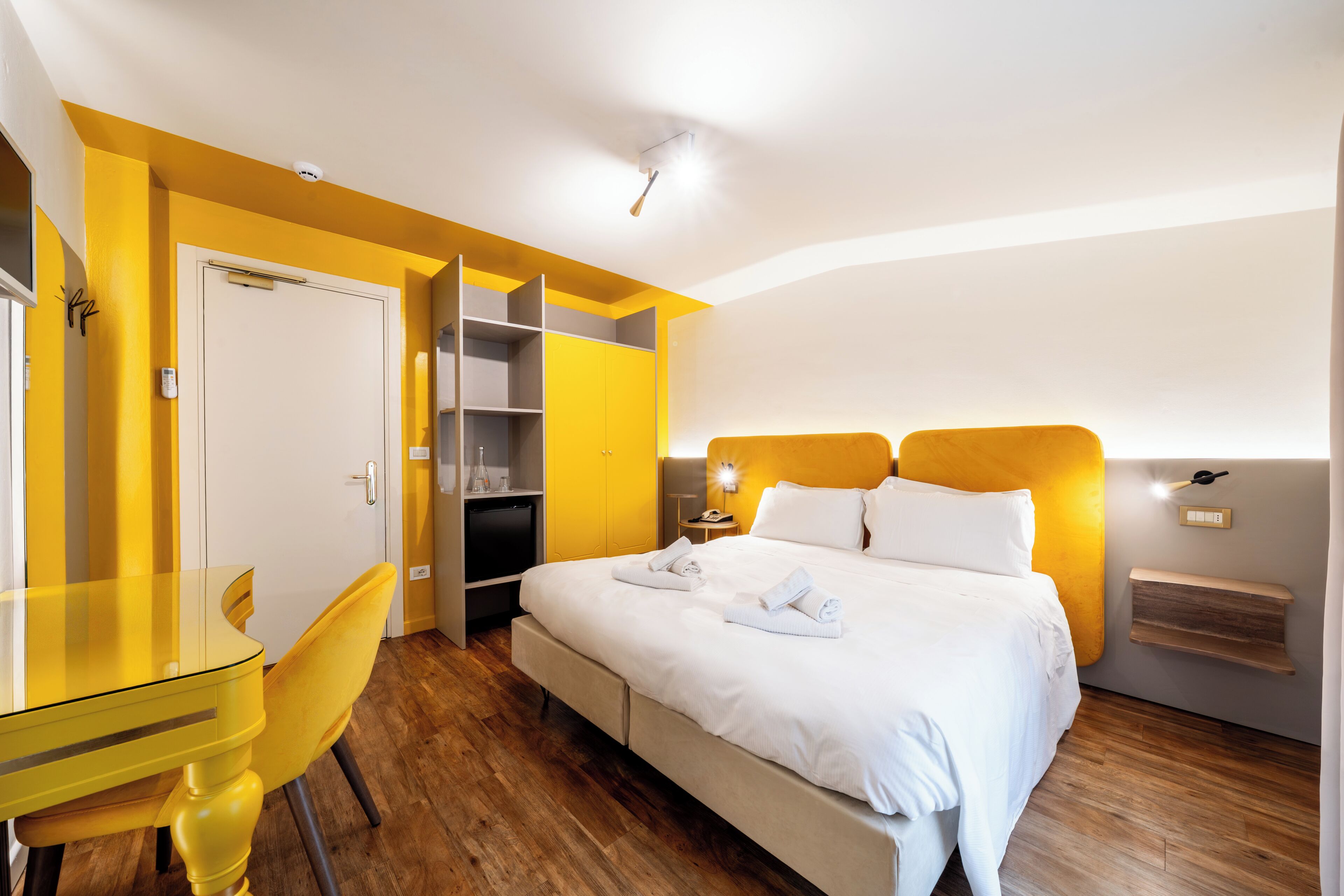 A hotel room with a bed, a desk, a chair, and a wardrobe.