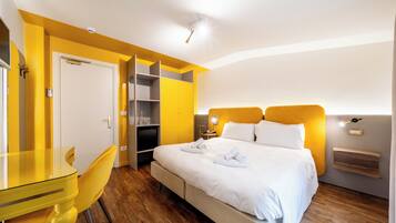 A hotel room with a bed, a desk, a chair, and a wardrobe.