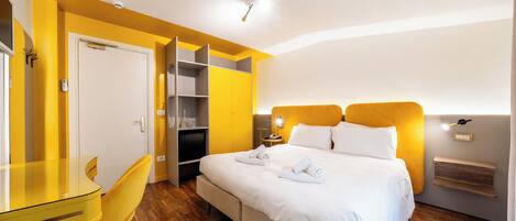 Una habitación de hotel con cama, escritorio, silla y armario.