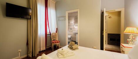 A hotel room with a bed, a television, a chair, a bathroom, and a door leading to another room.