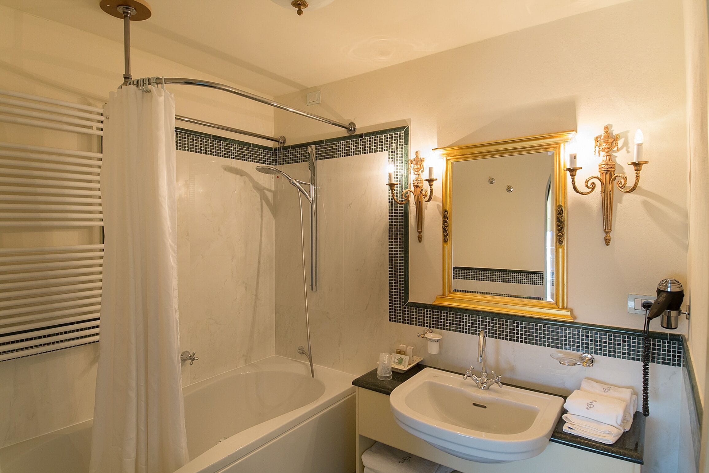Een badkamer met een bad, douche, wastafel en spiegel.
