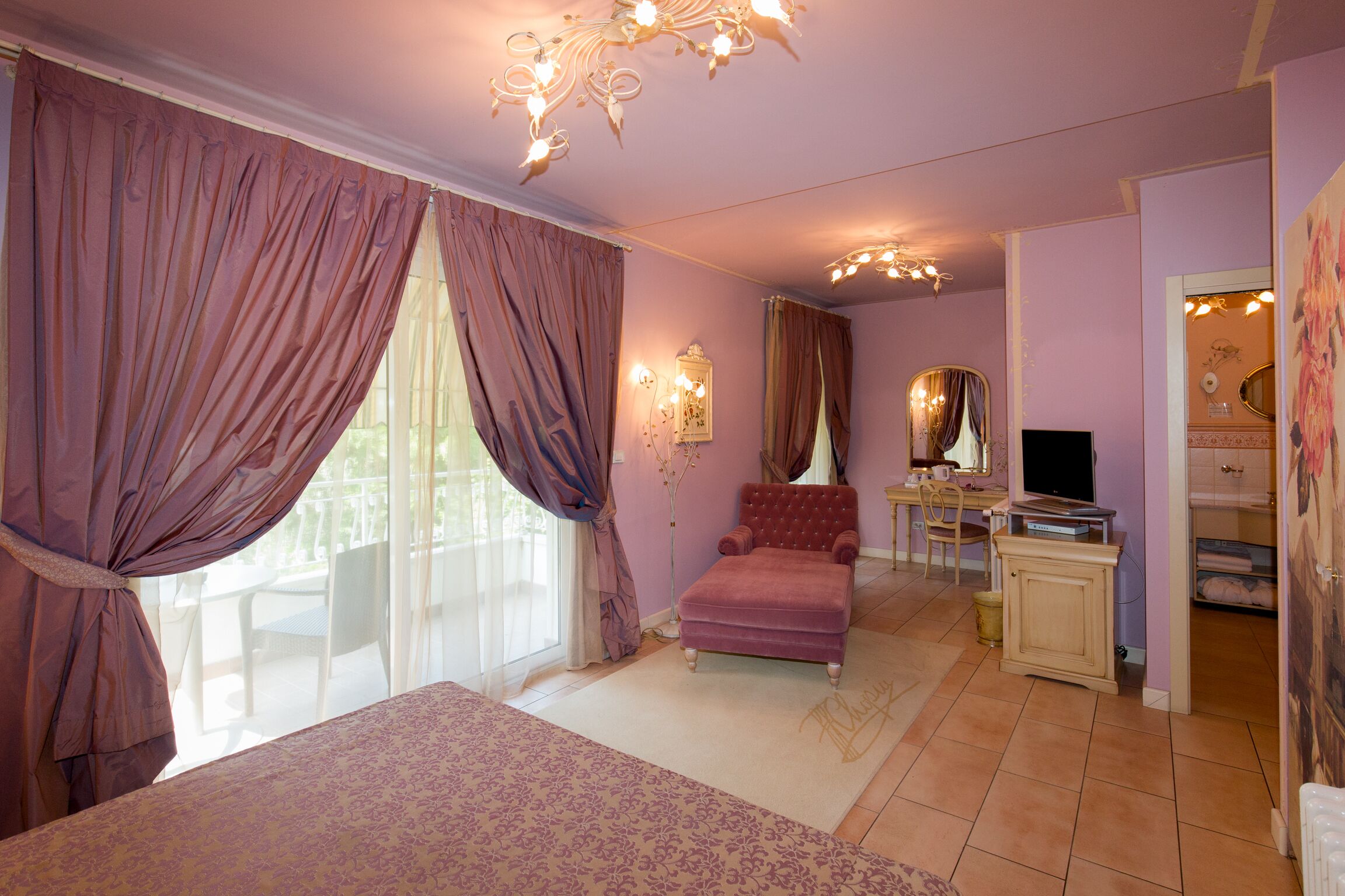 A bedroom with a bed, a chair, a desk, and a television.
