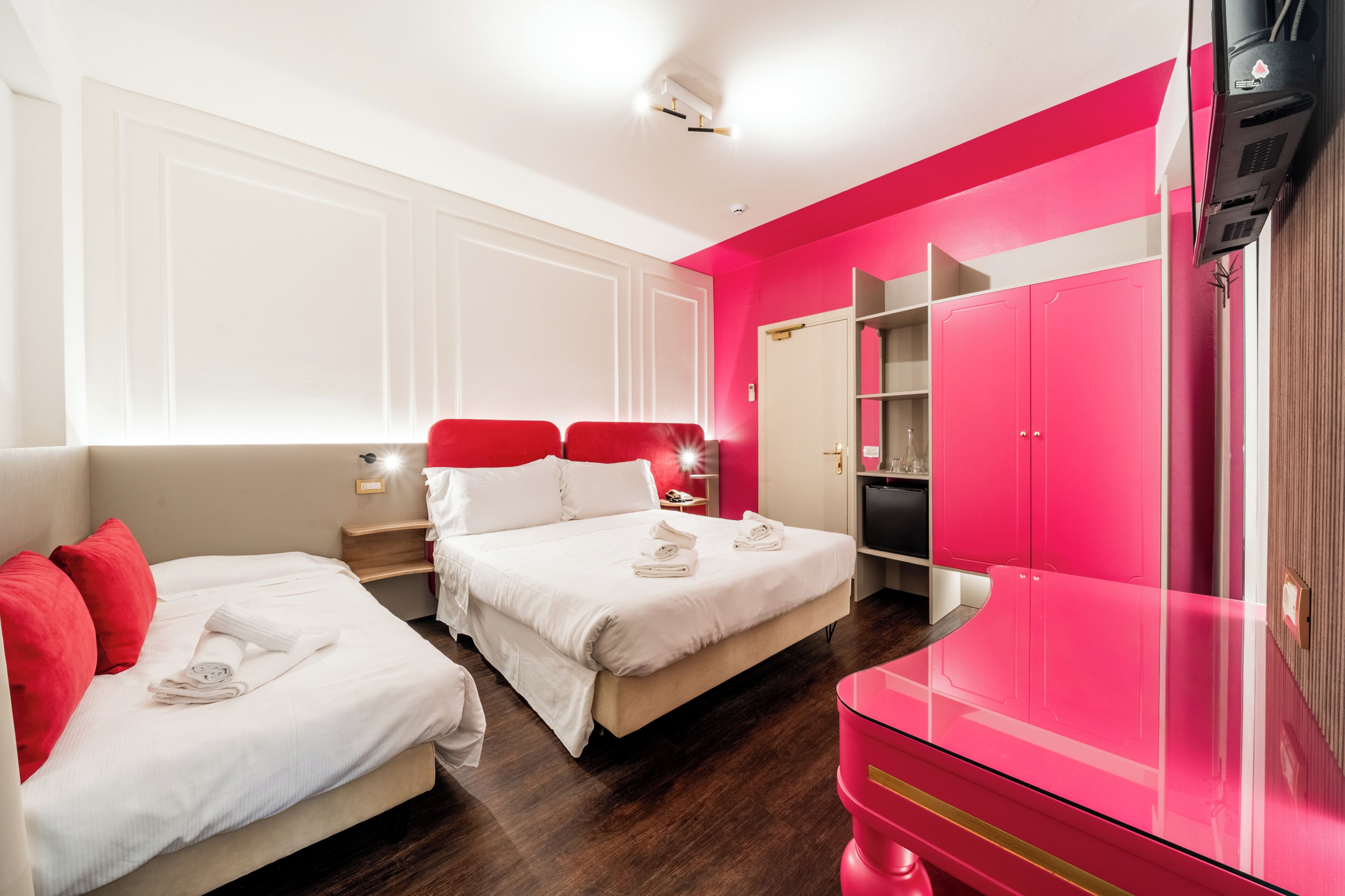A hotel room with two beds, a wardrobe, and a TV.