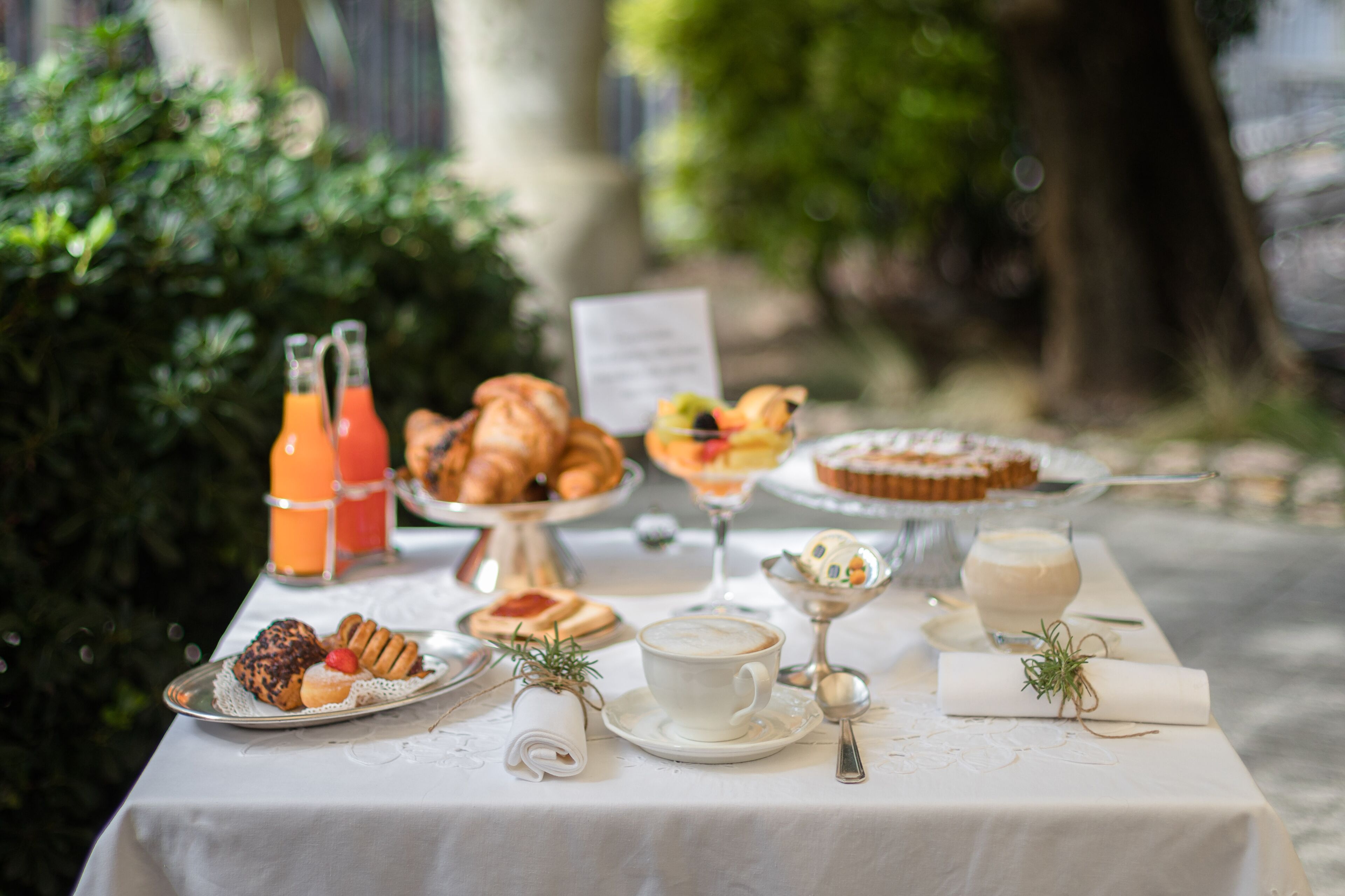 A table set with pastries, drinks, and a menu in an outdoor setting.