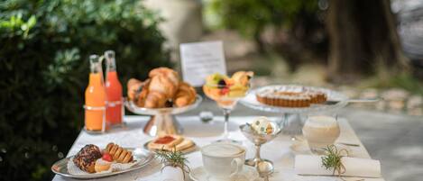 A table set with pastries, drinks, and a menu in an outdoor setting.