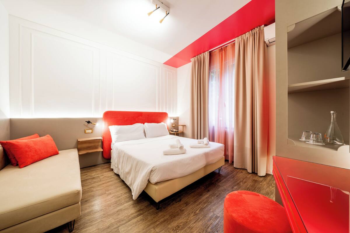 A hotel room with a bed, a sofa, a TV, and a desk.