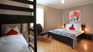 Un dormitorio con dos camas, una silla, una mesita de noche y un cuadro en la pared.