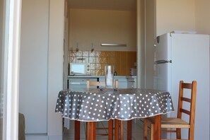 A small kitchen with a dining table covered by a polka dot tablecloth, a refrigerator, and a microwave.