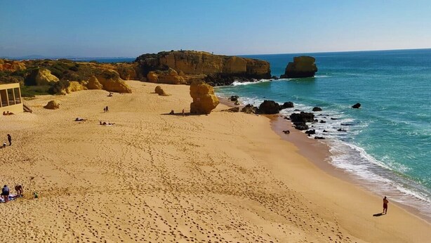 A beach with clear blue waters, rocky formations, and a few people. - OURASOL 2 Bedroom Apartment in Santa Eulalia, Albufeira Centre  (Albufeira)