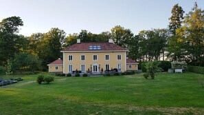 Stately building with a central entrance and symmetrical facade, set amidst a serene and lawn.