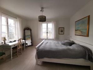 Relax in a serene bedroom with a large bed, desk, and full-length mirror.