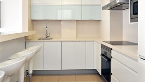 A modern kitchen with white cabinetry, a stainless steel sink, and a built-in oven. - Minimal, sea views apartment first line (Santa Margalida - Can Picafort/Son Serra Marina)
