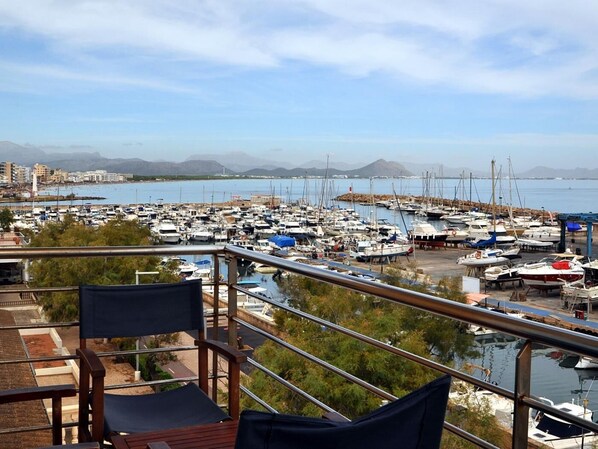 A marina with numerous boats docked, a clear sky, and distant mountains.