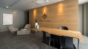 Una moderna área de recepción con un mostrador de madera, sillas negras, un jarrón blanco y una chimenea decorativa.