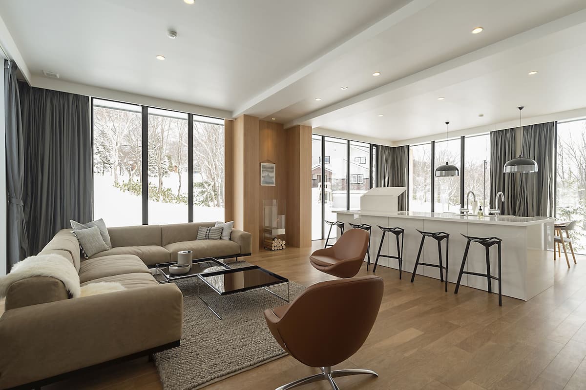 A modern living room with a sofa, coffee table, and a dining area with bar stools.