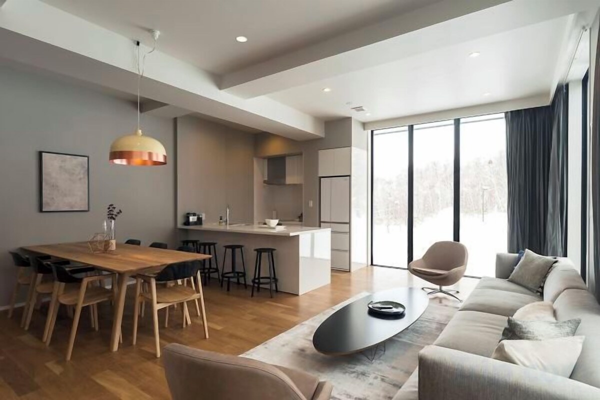 A modern living space with a dining area, kitchen, and seating area.