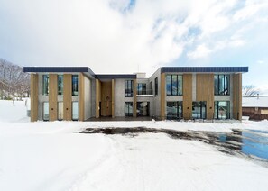 Un edificio moderno de varios pisos con amplios ventanales y una combinación de madera y hormigón.