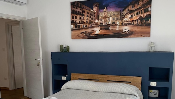 A neatly arranged hotel room with a bed, a bedside table with towels, a headboard, and a wall-mounted air conditioner.