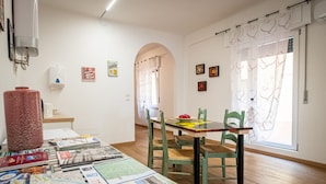 A dining area with a table set for two, a water dispenser, and a view through an arched doorway.