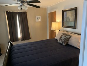 Hotelkamer met een bed, een plafondventilator, een nachtkastje met een lamp en een lijst aan de muur.