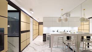 Een moderne keuken met witte kasten, een marmeren vloer en hanglampen.