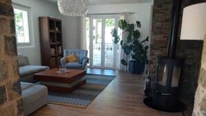 Ein Wohnzimmer mit einer Couch, einem Couchtisch, einem Bücherregal und einer großen Küstertopf-Pflanze.