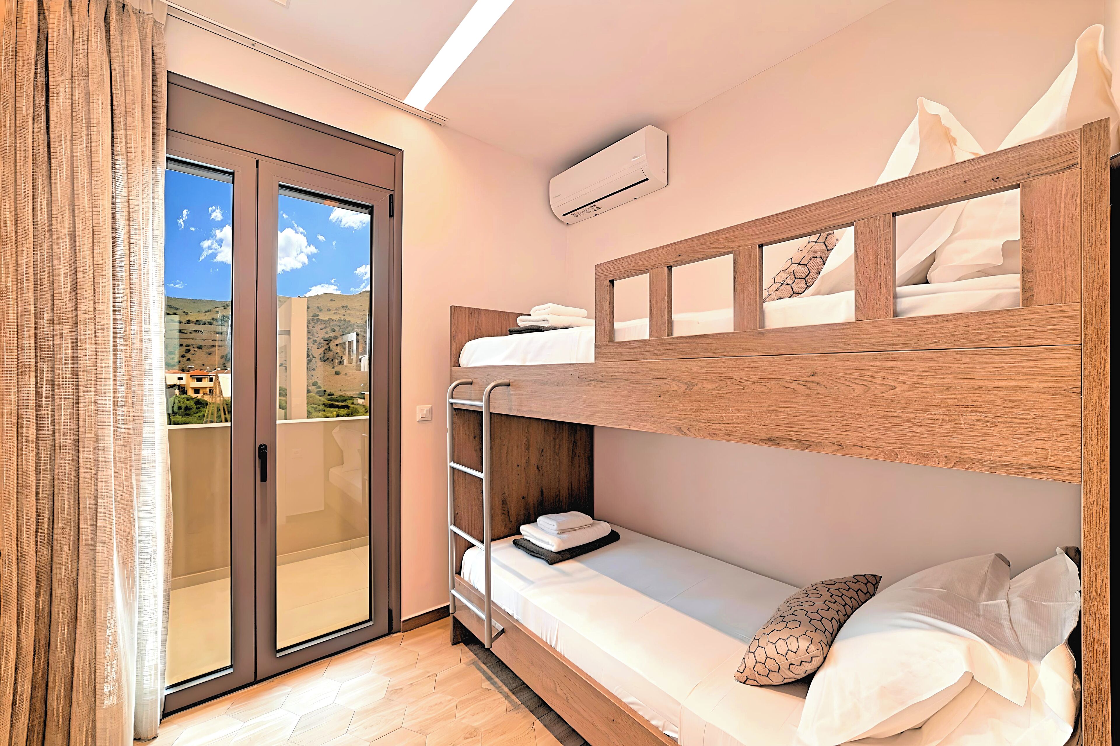A bunk bed room with a sliding glass door to a balcony, a built-in ladder, and a mounted air conditioner.