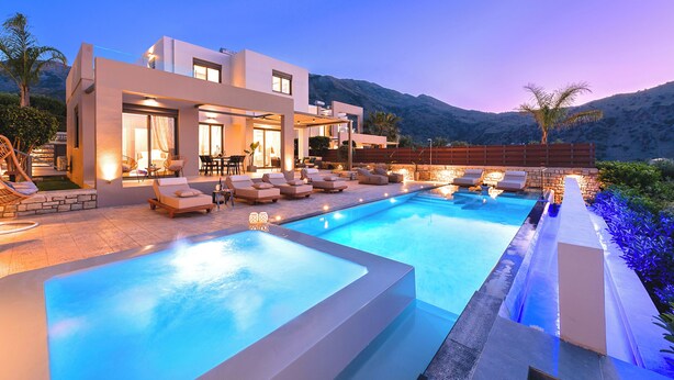 A modern house with a swimming pool, outdoor seating, and a mountain backdrop.