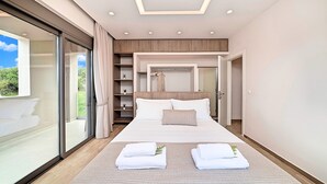 A modern bedroom with a large bed, a walk-in closet, and a sliding glass door to a balcony.