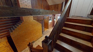 Eine Holztreppe mit einer Ziegelwand und einer Holzbalkendecke.
