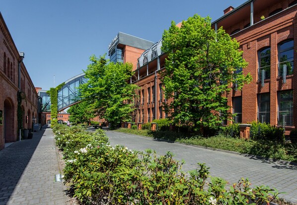 A pathway flanked by brick buildings with large windows and a glass structure.