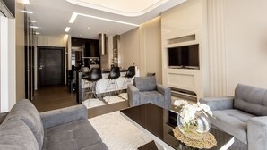 Una sala de estar moderna con sofás grises, una mesa de centro y un televisor montado en la pared.