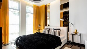 Un dormitorio moderno con una cama grande, una mesita de noche, una lámpara y vistas al exterior.