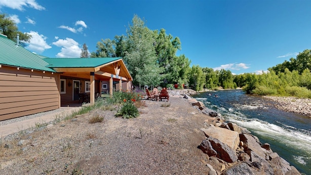 Un chalet doté d’un patio couvert et offrant une vue sur la rivière.