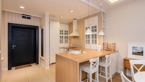 A modern kitchen with white cabinetry, a central island with bar stools, and pendant lighting. - Super-Apartamenty City Park II (Poznan)