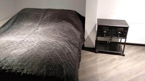A room with a bed, a small table, and a radiator.