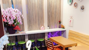 A dining area with a wooden table and chairs, a potted plant, and a shelf with decorative items. - Guanjing Apartment (Tokyo)