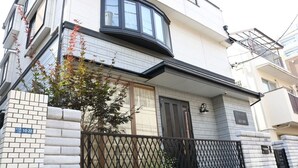 A multi-story residential building with a curved bay window, a dark front door, and a brick entrance. - Guanjing Apartment (Tokyo)