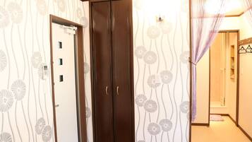 A hallway with a patterned wallpaper, a wooden door, and a purple curtain.