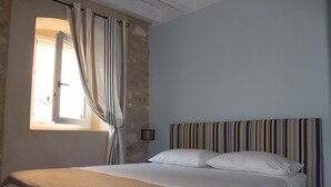 Un dormitorio con cama, cortinas, lámpara y ventana.