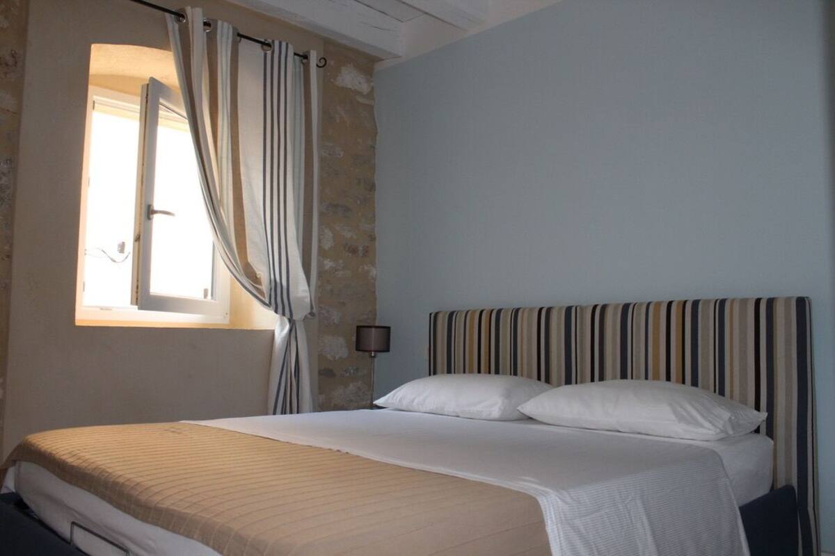 Ein Schlafzimmer mit einem Bett, Vorhängen, einer Lampe und einem Fenster.