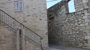 Una estrecha escalera de piedra que sube hacia un edificio con un muro de piedra rústica.