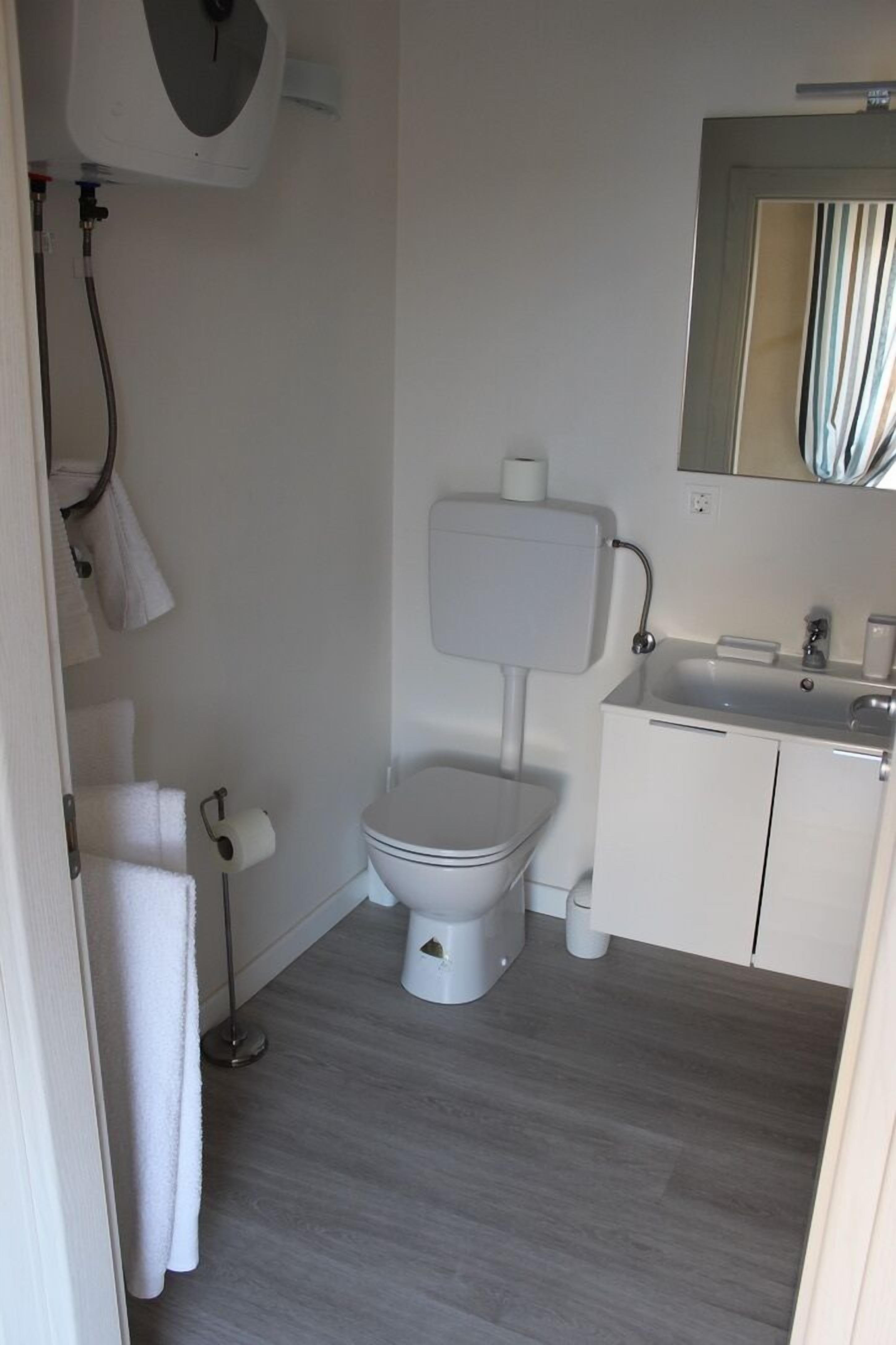 A small, modern bathroom with a toilet, sink, and mirror.