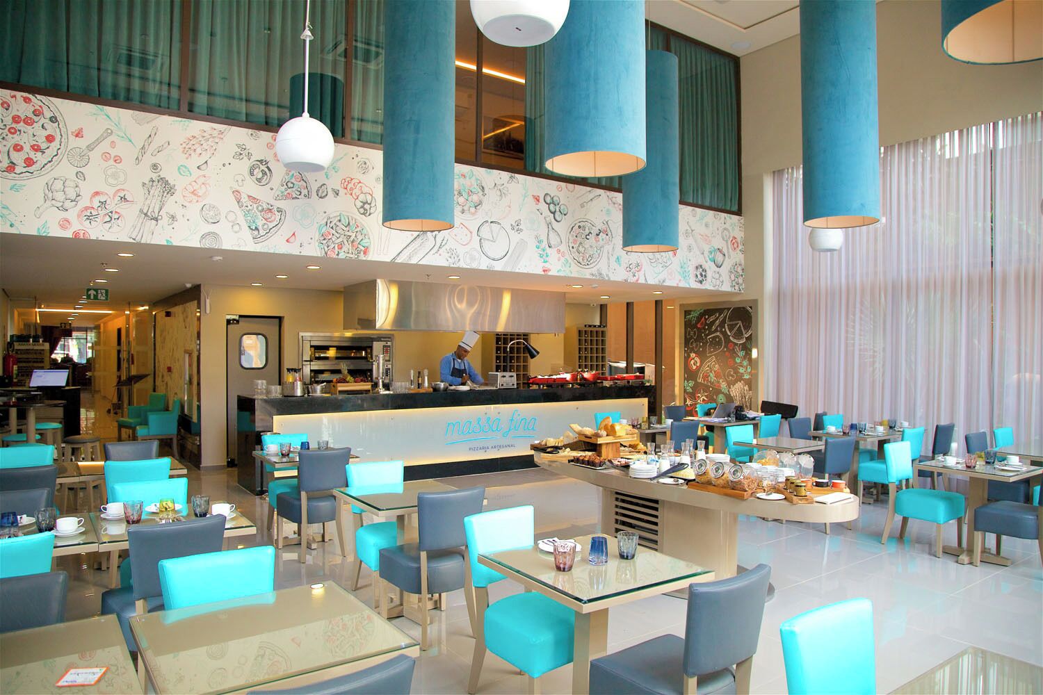 Ein Restaurant mit einer Theke, blauen Stühlen und einer Küche im Hintergrund.