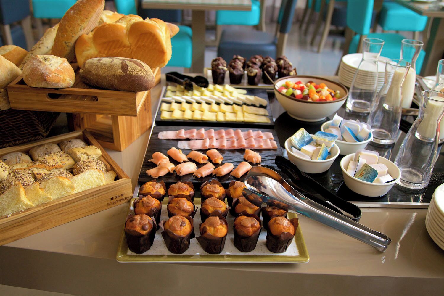 A buffet table with various food items including bread, pastries, and cheese.