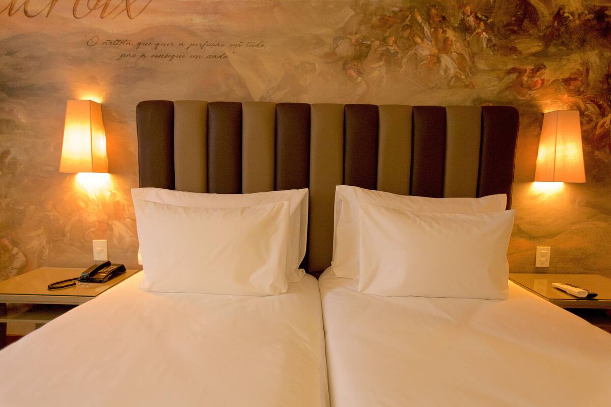 A double bed with a headboard, two bedside lamps, and a telephone on the nightstand.