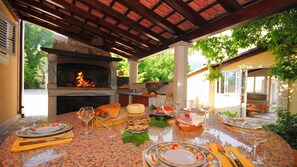 Enjoy al fresco dining in this outdoor space with a fireplace and grill, perfect for a meal with family and friends.