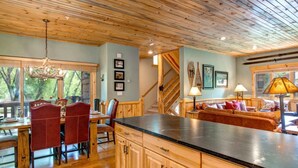 A spacious kitchen with wooden cabinets, a dining area with red chairs, and a cozy seating area with a sofa and cushions.