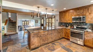 A spacious kitchen with wooden cabinets, granite countertops, stainless steel appliances, and a large island.